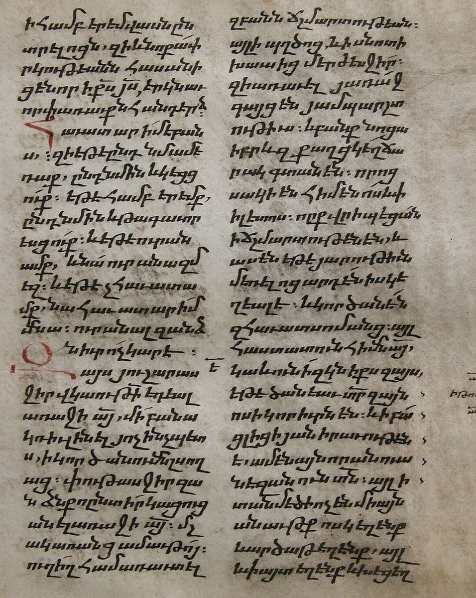 Parchment leaf with two columns of small, sloping bolorgir script in brown ink, with two red initial letters set into the text