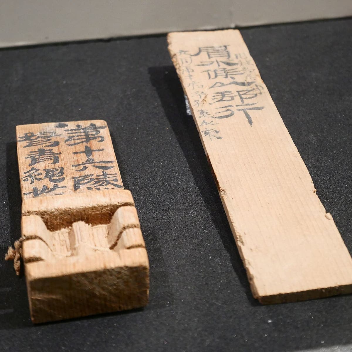 Two Han wooden sealing tags, one with a carved groove for a sealing cord, both inscribed with large bold characters