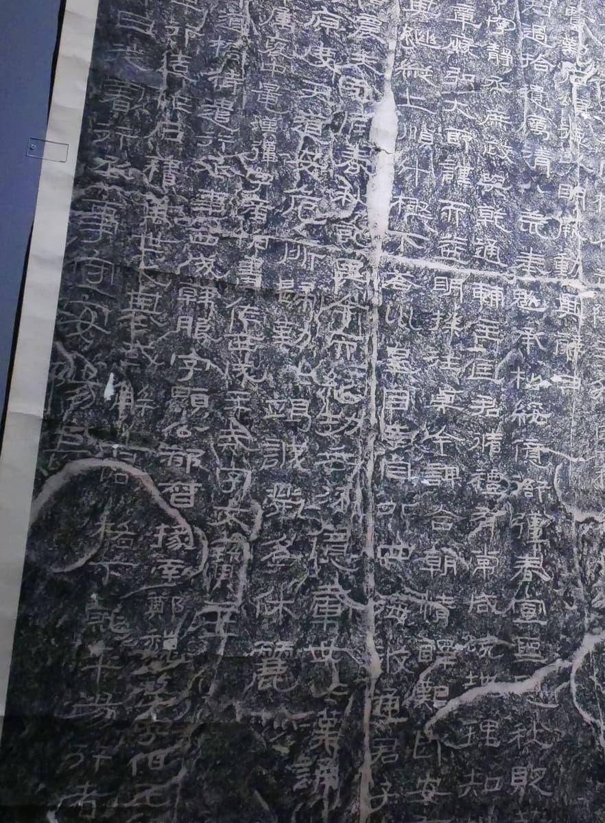 Detail of a large rubbing of a cliff inscription, white clerical characters on black with pale veins where the rock is uneven