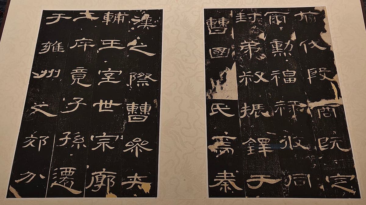 Two facing album leaves of a stele rubbing, each with large white clerical characters in a grid on a black ground