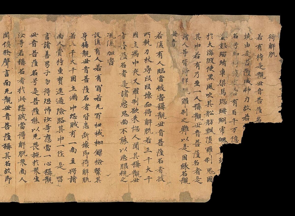 Torn sheet of a Dunhuang scroll with even columns of regular-script characters between faint ruled lines