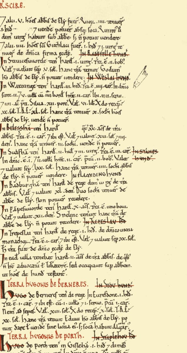 Right-hand column of a Domesday Book page: dense abbreviated Latin with red chapter headings and hundred names struck through in red