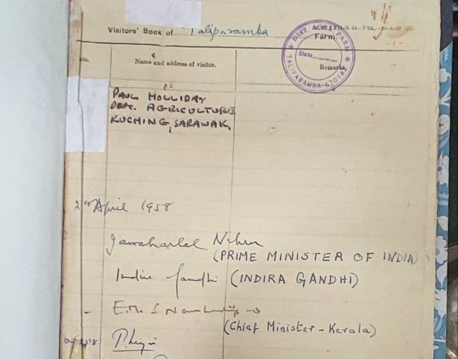 A phone photograph of an open visitors’ book with printed column headings, a purple rubber stamp and entries by several different people