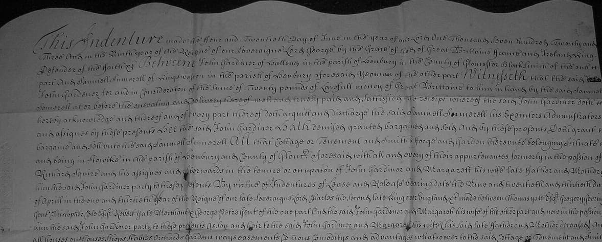 The upper half of a parchment deed with a wavy cut top edge and closely written engrossed lines beginning with a large decorated word