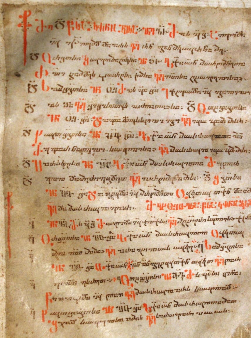 Parchment leaf of a Georgian church book written in dense brown Nuskhuri with large red Asomtavruli initials down the left margin