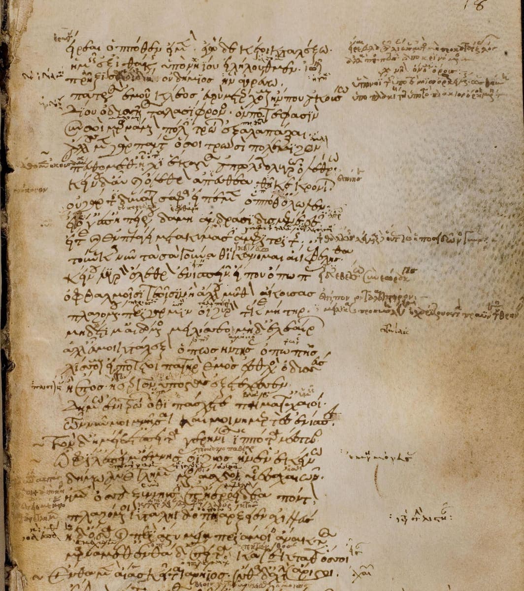 Manuscript page of Greek verse with small glosses written between every line and marginal notes down both sides, densest at the top right