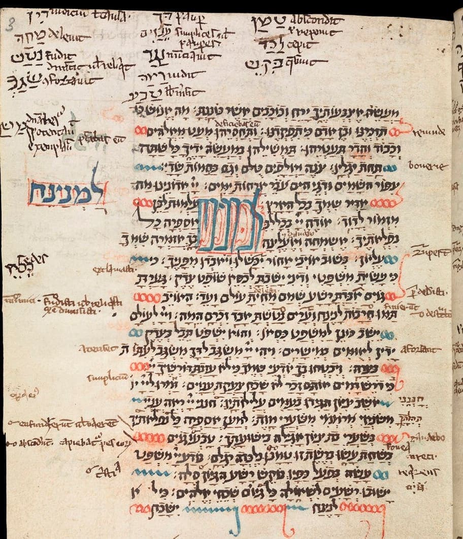 Small parchment page of pointed Hebrew Psalms with a red and blue decorated word panel and Latin annotations crowded into every margin