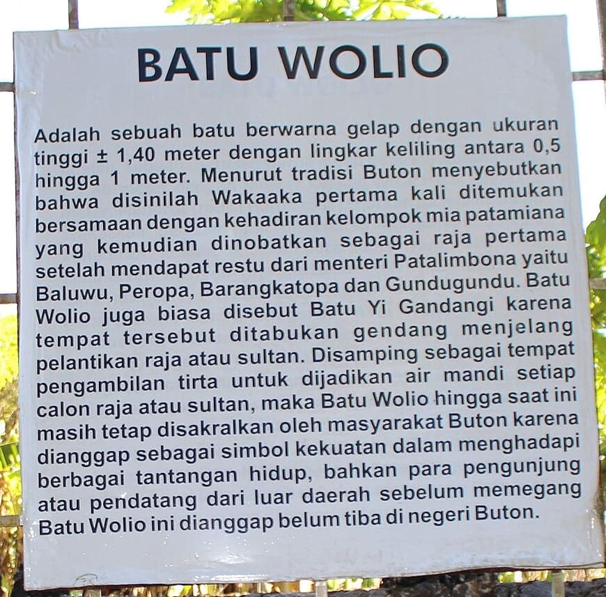 White enamelled information board in a steel frame carrying a heading and a single long paragraph of modern Indonesian