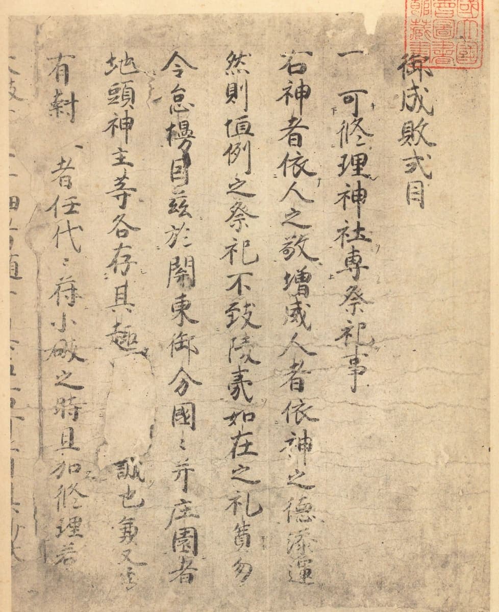 Facsimile of the opening page of a medieval Japanese law code, one article in large characters with tiny reading marks beside them and a red library seal at the top