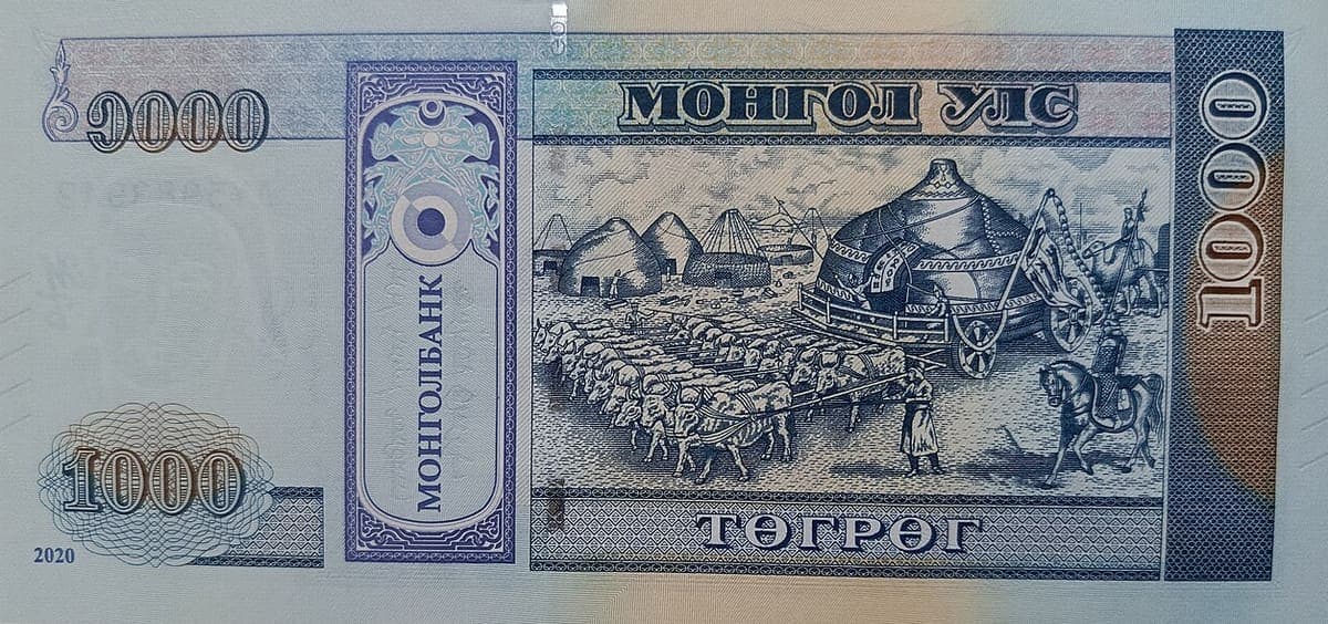 Reverse of a blue 1000-tögrög banknote with Cyrillic Mongolian text reading MONGOL BANK vertically in a decorated panel and an engraved migration scene
