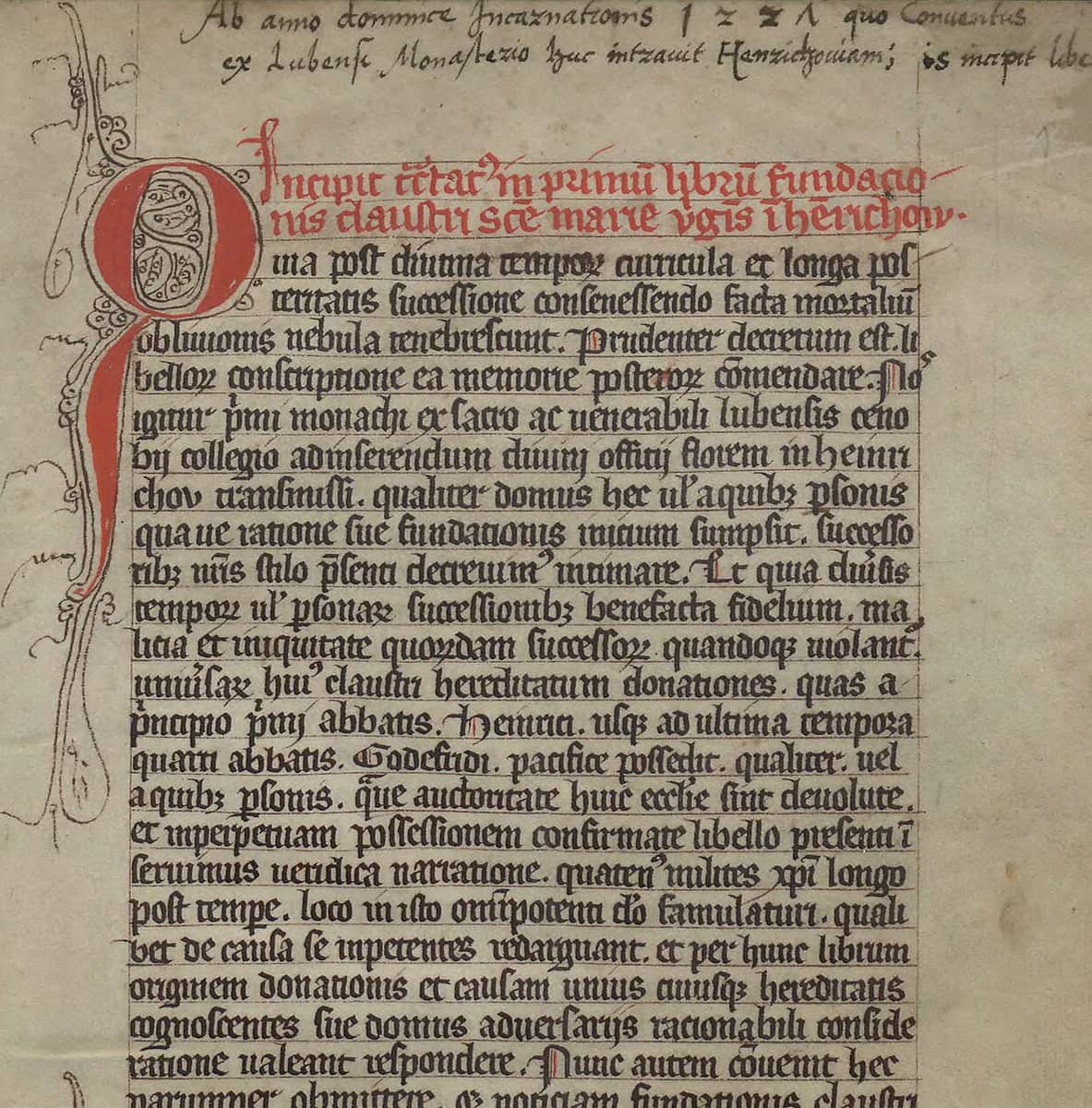 First page of a thirteenth-century monastic register, Gothic book script in a single column with a large red initial, red rubrics and a later cursive heading above the text