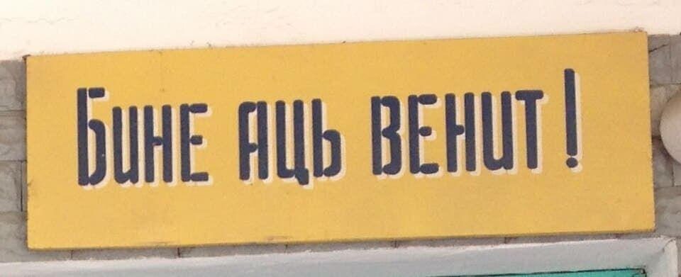 Yellow painted sign in Tiraspol reading BINE ATI VENIT in Moldovan Cyrillic letters