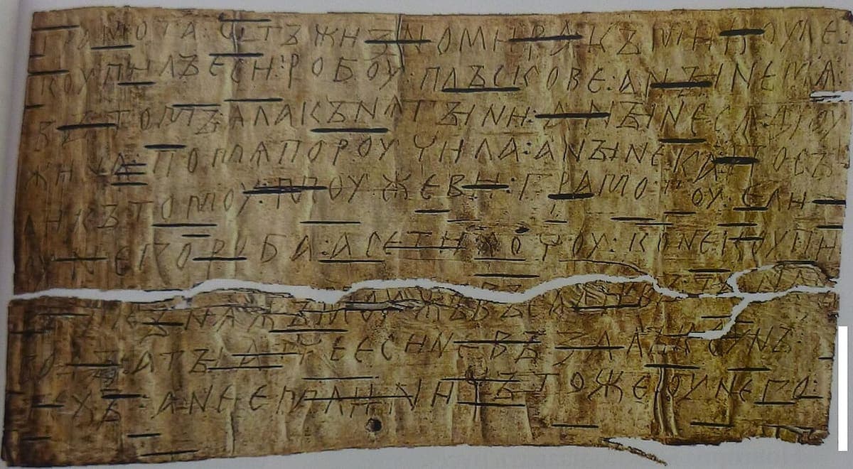 Sheet of birch bark broken across the middle, with nine lines of Cyrillic letters scratched into the surface