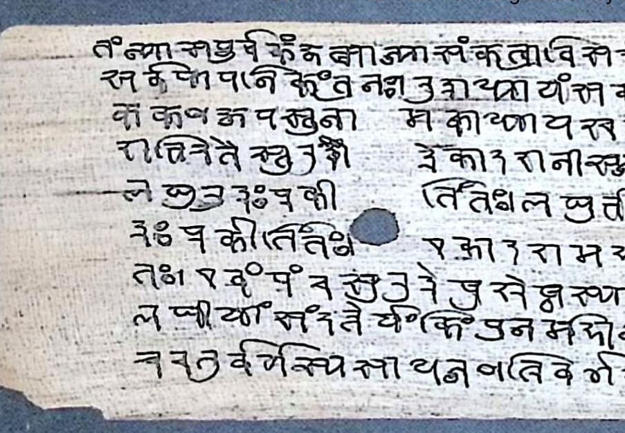 A palm leaf of large Nandinagari letters, the lines broken by a cord hole left clear near the middle of the leaf