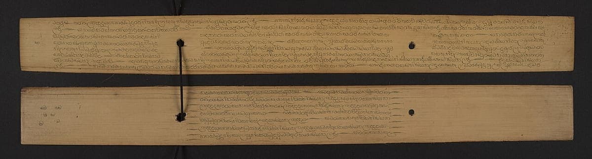 Two ola-leaf strips lying one above the other, incised with rounded Sinhala and Pali script and each pierced by two binding holes