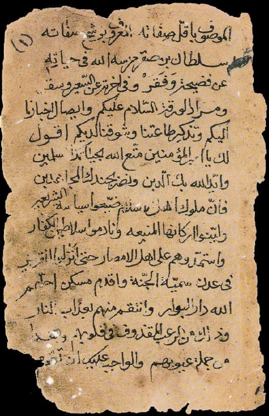 A small, worn sheet of Arabic-script cursive handwriting on aged, torn paper, its lines running right to left