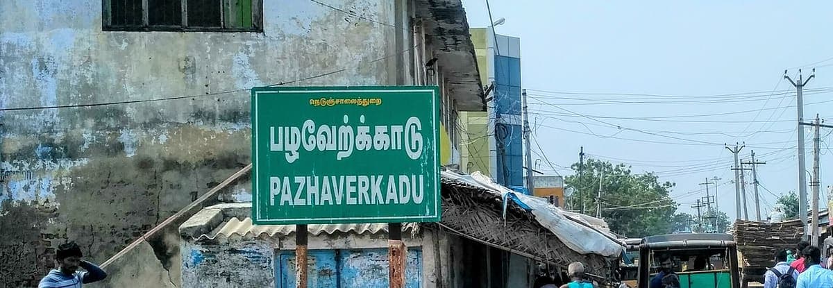 Green bilingual village name board reading Pazhaverkadu in Tamil and Pazhaverkadu in English on a street corner