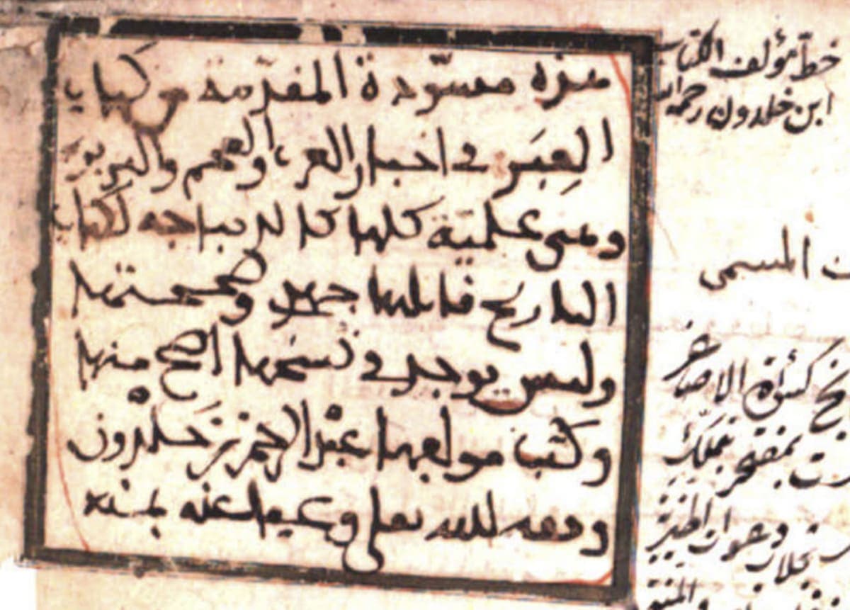 Close view of a framed handwritten note in a looping western Arabic hand, with a second column of writing to its right