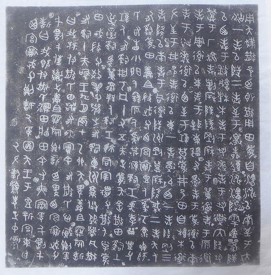 Square rubbing sheet of the San shi pan inscription, nineteen dense columns of white graphs on a grey-black ground