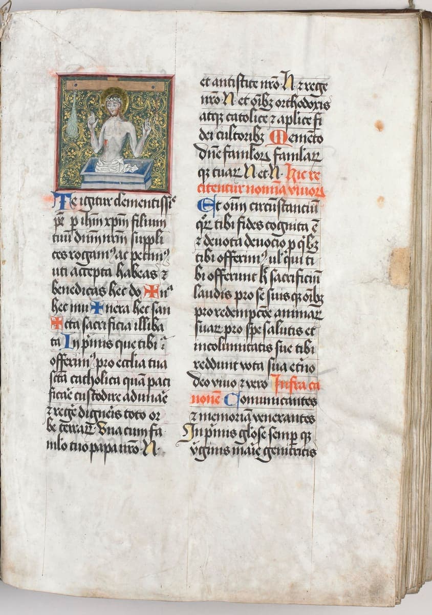 Right-hand page of a two-column Latin missal with red rubrics, blue and red initials and a small illumination of the Man of Sorrows