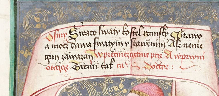 A painted banderole inscribed with four lines of Czech text in black and red, above the red-hooded head of the figure holding it