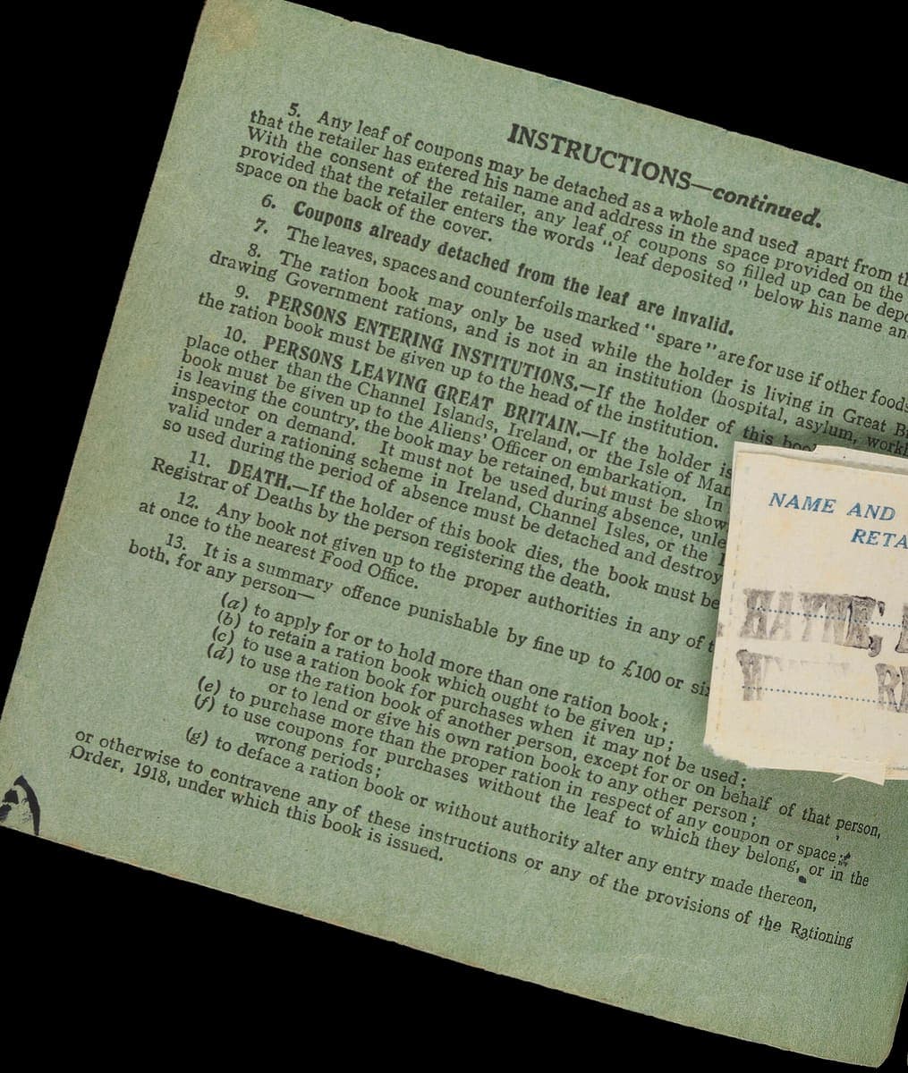 The instructions page of a wartime ration book, densely printed in small type with numbered clauses, a small paper slip lying across the right-hand edge