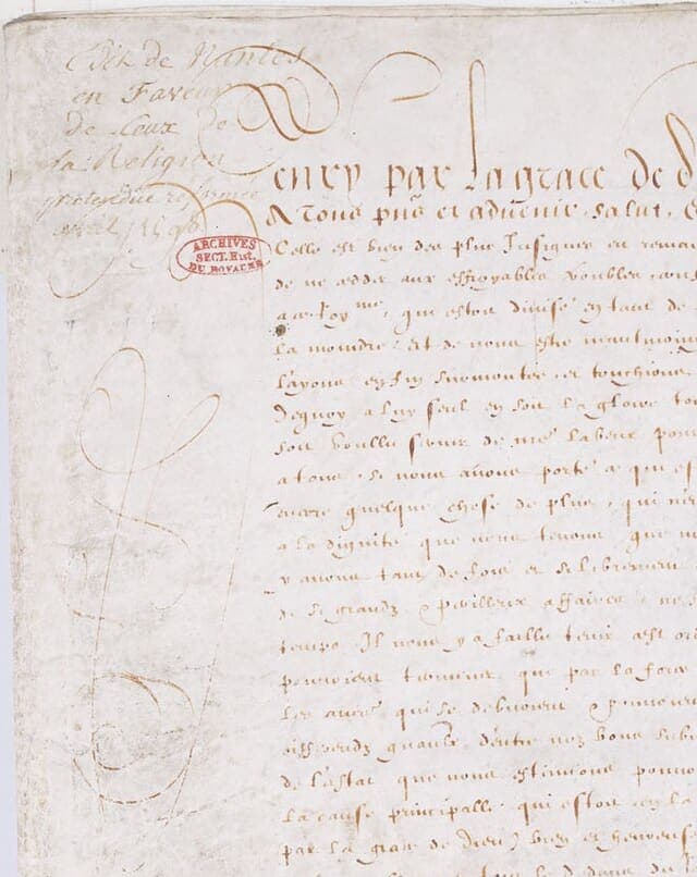 The head of a large parchment sheet with a royal name written in tall looping display letters above closely spaced lines of faded brown chancery script, and a title added in the left margin