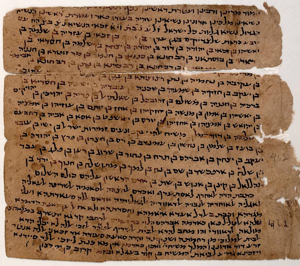 Four torn strips of brown paper carrying long lines of Hebrew genealogy in a broad semi-cursive, changing to Judeo-Arabic in the lower strips