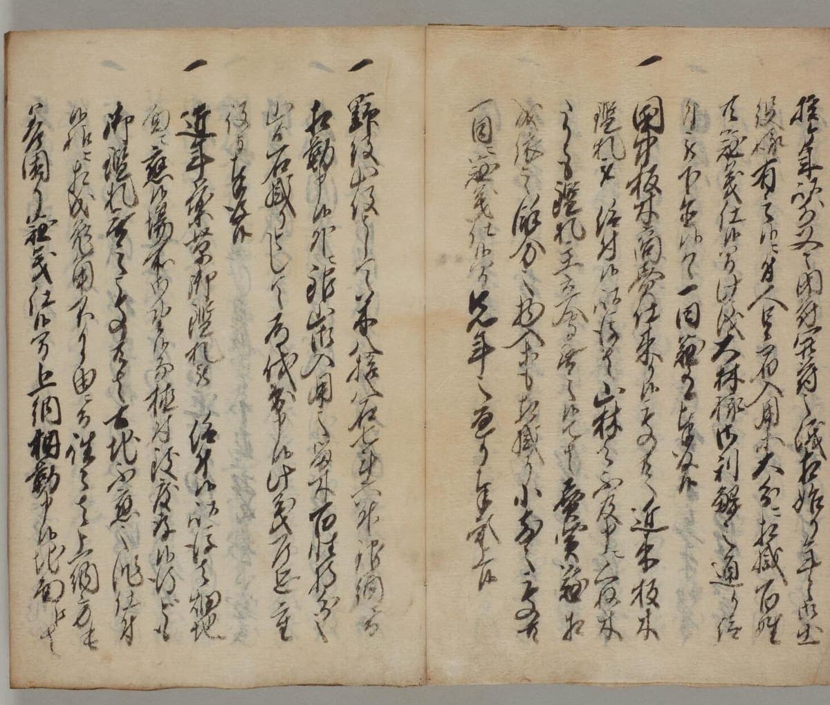Open booklet of thin paper filled with dense cursive Japanese, each paragraph beginning with a raised single stroke