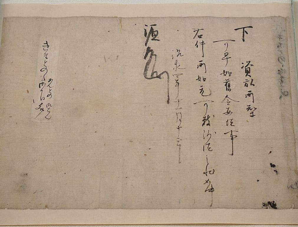 Twelfth-century Japanese land grant on a wide sheet, five short columns of characters and a very large drawn monogram, with a small kana note at the far left