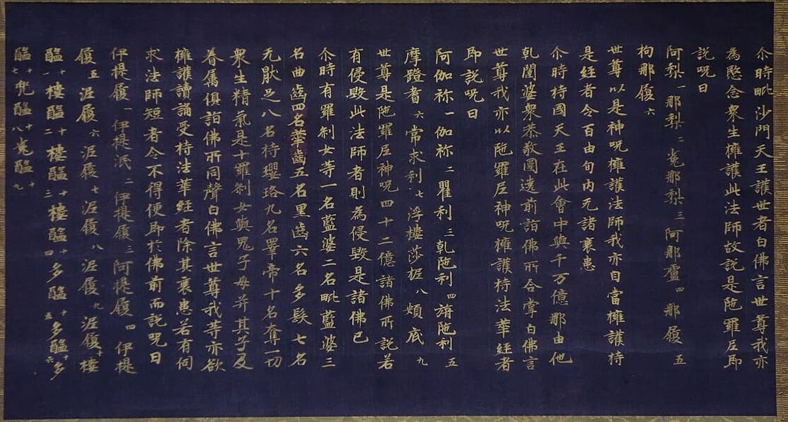 Detached sutra segment written in gold ink on indigo-dyed paper, ruled columns of Chinese characters with tiny numerals beside the transliterated spell