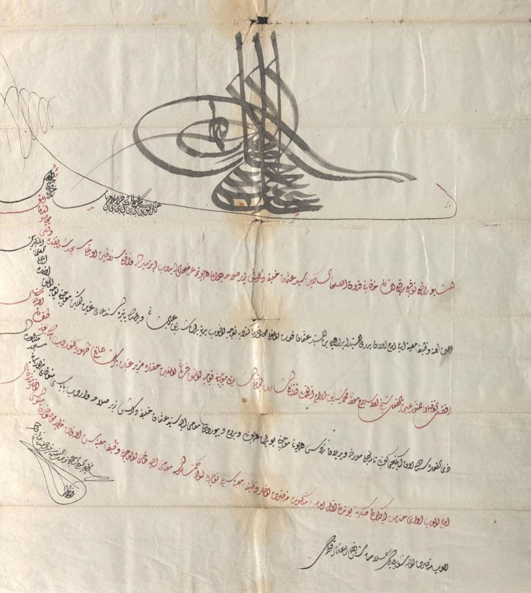 Ottoman document with a large black tughra above six rising lines in red and black, a vizier signature at the lower left and marginal notes down the left edge