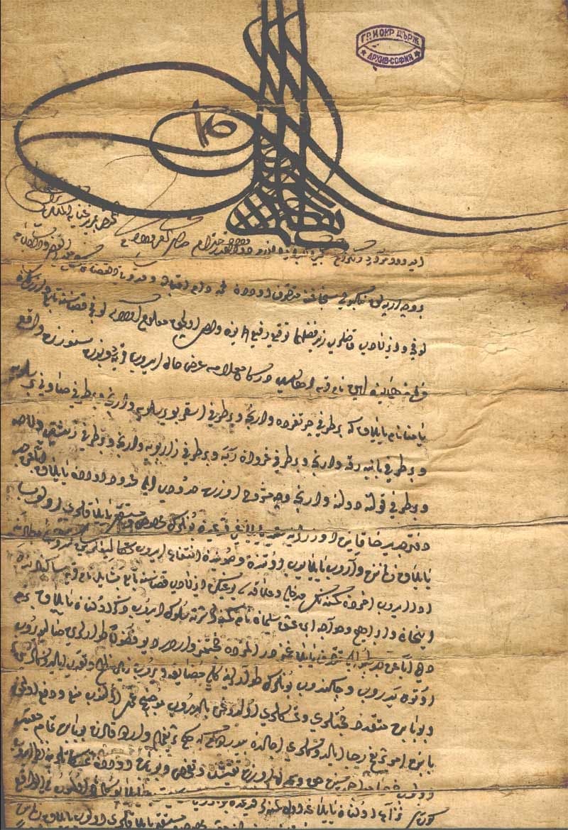 Brown leather document with a large black tughra at the top and about eighteen tightly written lines of Ottoman script filling the sheet