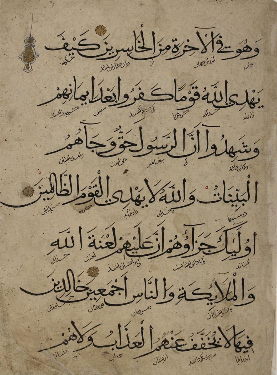 Seven lines of large sweeping Arabic script with tiny Persian words written diagonally beneath each Arabic word