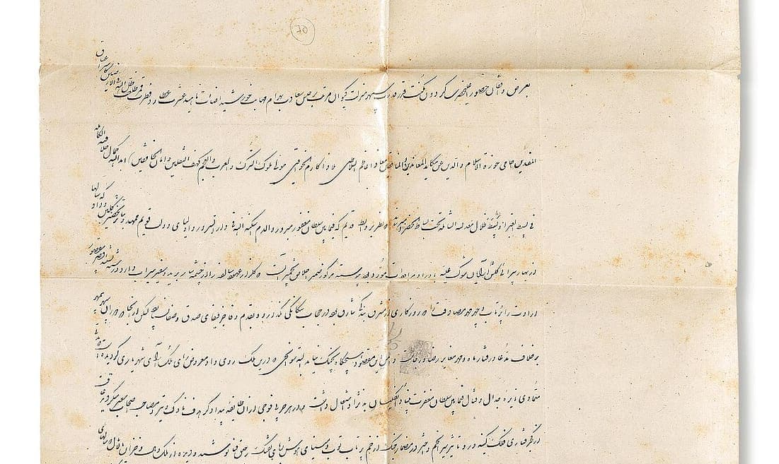 A folded sheet of pale paper with eight lines of small Persian, each ending in a short phrase that climbs above the line at the left edge