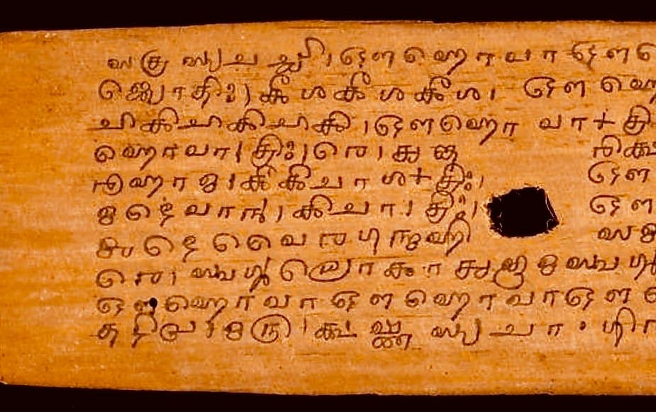 A palm leaf of southern Grantha with small marks and figures written above the line of text