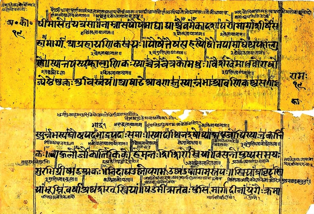 Two yellow folios with four large lines of Newar script each and a much smaller second hand written between and above the lines