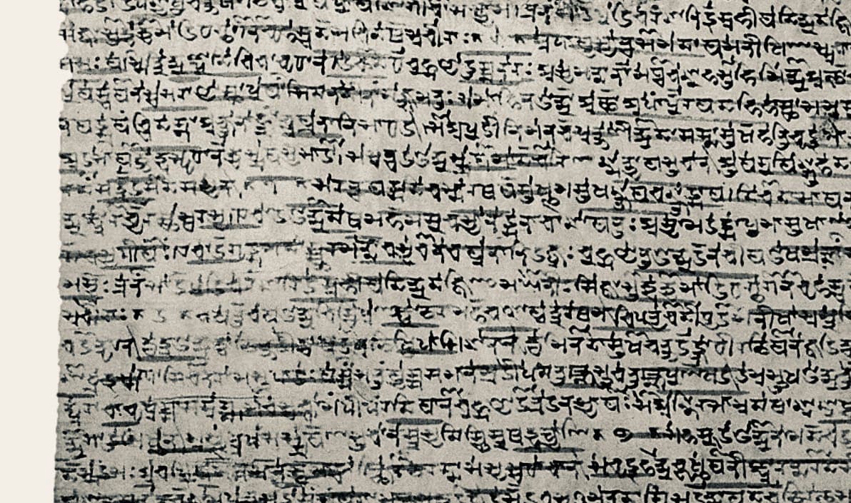 Dense grey manuscript leaf with about twenty lines of small angular writing, many syllables carrying a stroke underneath, and dark horizontal splits across the surface