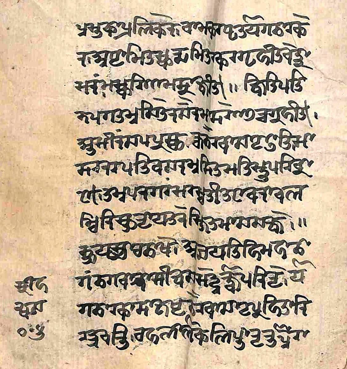 Worn folio with twelve lines of Śāradā writing, a vertical crease down the middle and three characters written vertically in the left margin
