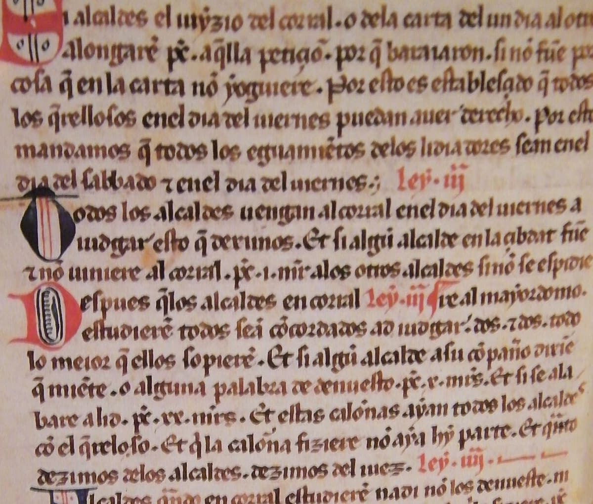 A column of rounded Gothic book script with red chapter headings and blue and red initials.