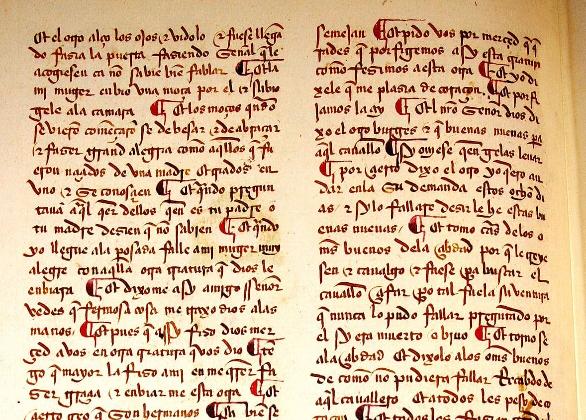 Two columns of red-brown Gothic cursive with red paraph marks, the lowest line cut through by the bottom edge of the frame.